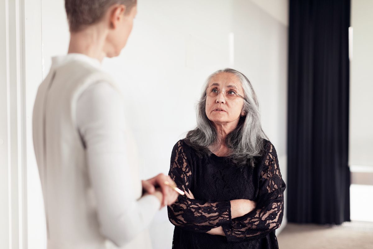 An employee with arms crossed in a serious conversation with the manager