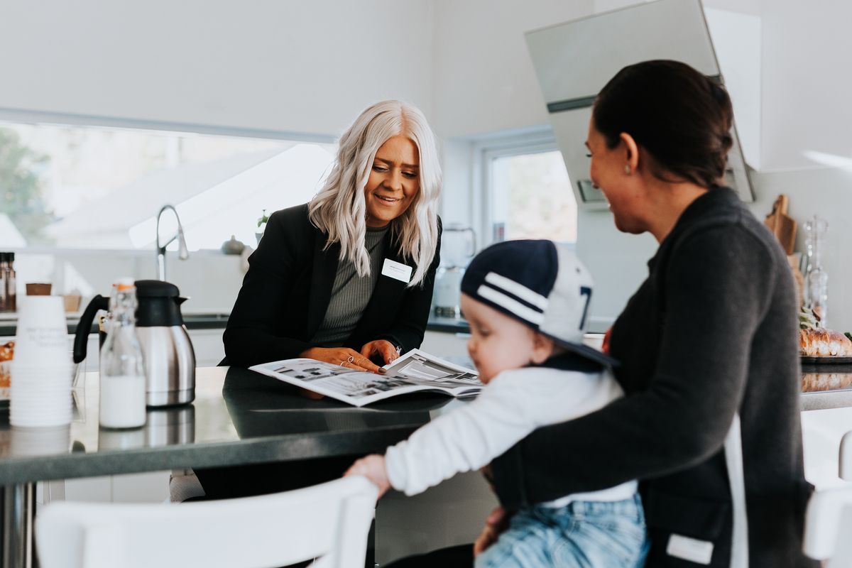 An estate agent showing papers to a customer at the kitchen counter