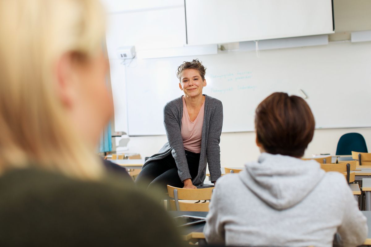 En kursledare i samtal med deltagarna i ett klassrum